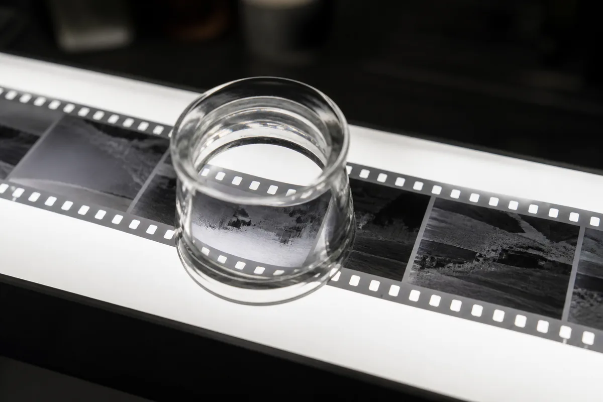 Loupe de table posée sur une bande de négatifs noir et blanc éclairée par le dessous